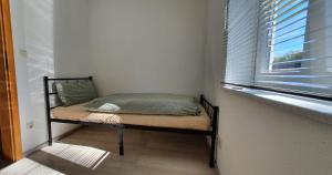 ein kleines Bett in einem Zimmer mit Fenster in der Unterkunft FN City Bungalow in Friedrichshafen