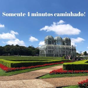 a conservatory in a park with flowers and plants at Bela Curitiba Hostel in Curitiba