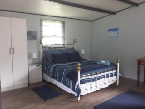 a bedroom with a bed with blue sheets and a window at Nadine's Self - Catering Accommodation in Stormsrivier