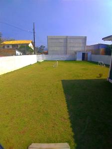 a large grassy yard with a building in the background at CASA PRAIA PINHEIRA e GUARDA EMBAU in Palhoça