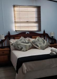 um quarto com uma cama com almofadas e uma janela em Nadine's Self-Catering Accommodation em Stormsrivier