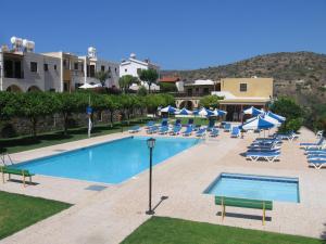 a large swimming pool with lounge chairs and umbrellas at Maria Villa in Pissouri