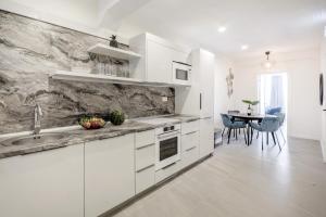 a white kitchen with a sink and a table at Million Sunsets Luxury Apartments in St Paul's Bay