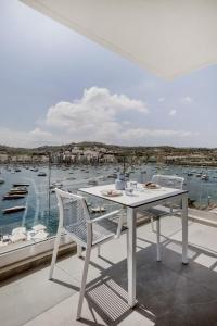 a white table and chairs on a balcony with a harbor at Million Sunsets Luxury Apartments in St Paul's Bay