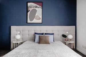 a bedroom with a large white bed with blue walls at Million Sunsets Luxury Apartments in St Paul's Bay