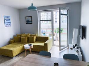 a living room with a yellow couch and a window at Słoneczne Tarasy by Marta in Dziwnówek