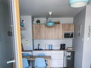 a kitchen with a table and blue chairs in a room at Słoneczne Tarasy by Marta in Dziwnówek
