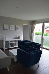 a living room with blue chairs and a table at MOIN & AHOI Ferienwohnung in Boiensdorf