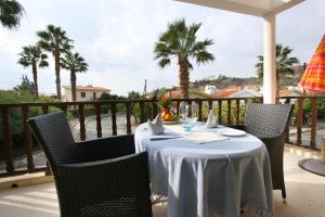 stół z białą tkaniną na balkonie z palmami w obiekcie Maria Villa w mieście Pissouri