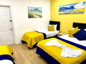 a room with two beds with yellow and blue at London 2 Bedroom Apartment, Kitchen, Reception and Private Garden in London