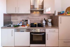 a kitchen with white cabinets and a stove top oven at Ferienwohnung Big Family in Ichenhausen