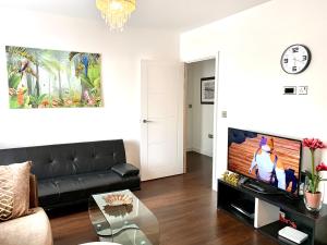 a living room with a black couch and a tv at 2-Bedrooms Modern Apartment next to Velodrome, Lounge, Balcony, Parking, ABBA in London