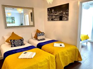 two beds in a room with yellow and blue at 2-Bedrooms Modern Apartment next to Velodrome, Lounge, Balcony, Parking, ABBA in London