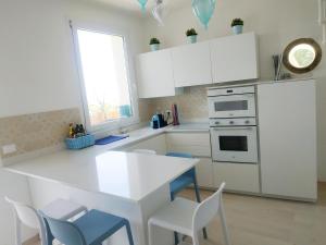 una cocina con armarios blancos y una mesa y sillas blancas. en AMPHIORAMA, en La Spezia