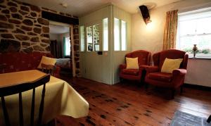 a living room with two chairs and a table and a room with a table at Rosies Cottage in Maghera