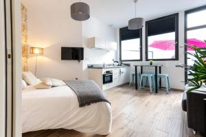 a bedroom with a bed and a kitchen with windows at Koaloft - Terrasse privée - Lorient centre in Lorient