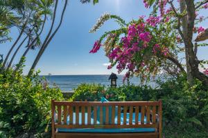 a wooden bench sitting in front of the ocean at Santai Hotel in Amed