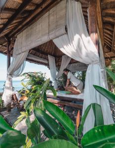 a man sitting on a bed in a hut on the beach at Santai Hotel in Amed