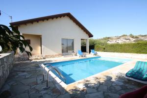 a swimming pool with two chairs and a house at Hilltop Chalet in Pissouri