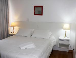 una camera da letto con un letto bianco con due asciugamani di SANTA CLAUS 2 - Centro de Gramado a Gramado