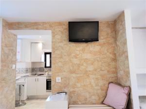 een woonkamer met een tv aan een stenen muur bij 7. Luxurious sea view rooftop suite in the center! in Rhodos-stad
