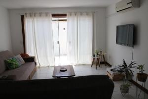 a living room with a couch and a tv at Búzios Lofts in Búzios