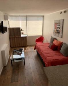 sala de estar con sofá rojo y mesa en Departamento en el Golf, en Santiago