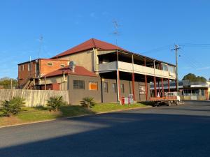a large building with a red roof on the side of the street at Railway Motel Dorrigo Commercial Hotel in Dorrigo