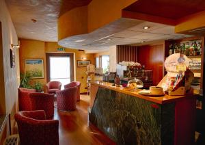 a restaurant with a bar with red chairs at Hotel Au Soleil in Saint Vincent