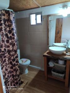a bathroom with a sink and a toilet and a mirror at El Destacamento in Villa Serrana