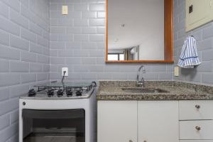 a white kitchen with a sink and a mirror at Apartamento Boa Viagem Niterói Rio de Janeiro in Niterói +43 photos