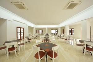 a dining room with tables and chairs and windows at KHAS Ombilin Hotel in Sawahlunto