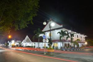 een wit gebouw op een straat 's nachts bij KHAS Ombilin Hotel in Sawahlunto