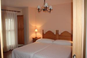 a bedroom with a white bed and a chandelier at Casa 1340 in Mora de Rubielos