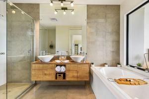 een badkamer met 2 wastafels, een bad en een spiegel bij The Ridge at Maleny in Maleny +20 foto's