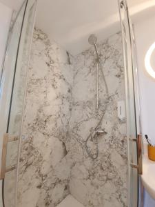 a shower in a bathroom with a marble wall at Yellow Studio in Mons