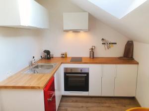 a small kitchen with white cabinets and a sink at Yellow Studio in Mons