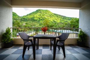 a table and chairs on a balcony with a mountain at Indradhanush Hill Resort in Mulshi