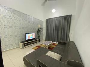 salon z kanapą i telewizorem z płaskim ekranem w obiekcie Homestay ayer keroh mitc w Malakce
