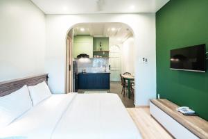 a bedroom with a white bed and a green wall at Mecozy Apartel in Ho Chi Minh City