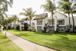 an exterior view of a building with palm trees at Canonnier Beachcomber Golf Resort & Spa in Pointe aux Cannoniers