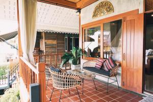 a porch with chairs and a table on a balcony at Buri Gallery House in Chiang Mai