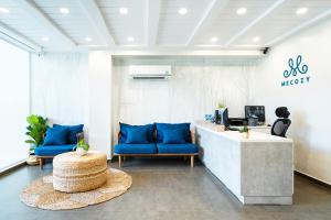 a lobby with blue chairs and a reception desk at Mecozy Apartel in Ho Chi Minh City