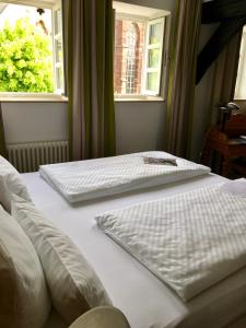 2 weiße Betten in einem Schlafzimmer mit 2 Fenstern in der Unterkunft Alt Warburg in Warburg