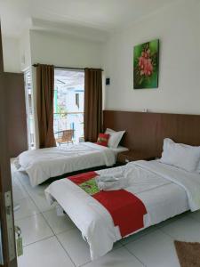 a hotel room with two beds and a window at Maulana Hills Syariah Hotel in Lembang
