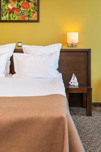 um quarto com uma cama e uma mesa com um candeeiro em Vega Hotel em Galaţi