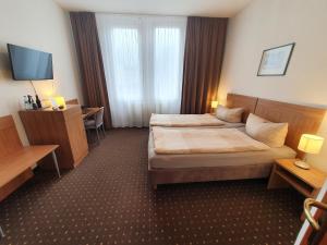 a hotel room with two beds and a desk at Pension am Heusteig in Stuttgart