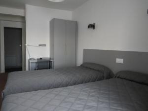 a bedroom with two beds and a white cabinet at Hôtel de Clèves in Nevers