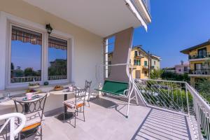 een patio met een tafel en stoelen op een balkon bij Appartamento La Maison Fleurie - Happy Rentals in Desenzano del Garda
