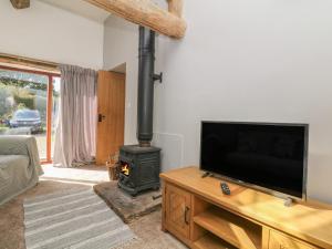 sala de estar con TV de pantalla plana y estufa de leña en The Old Cart House, en Edale